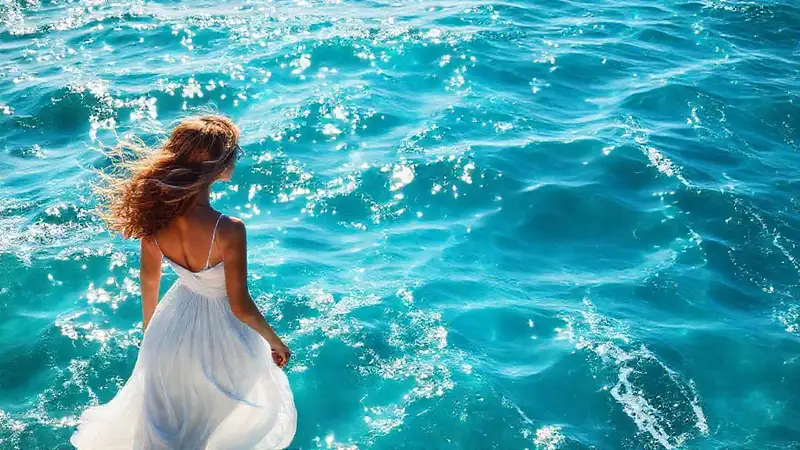 Silueta femenina elegante en mar turquesa